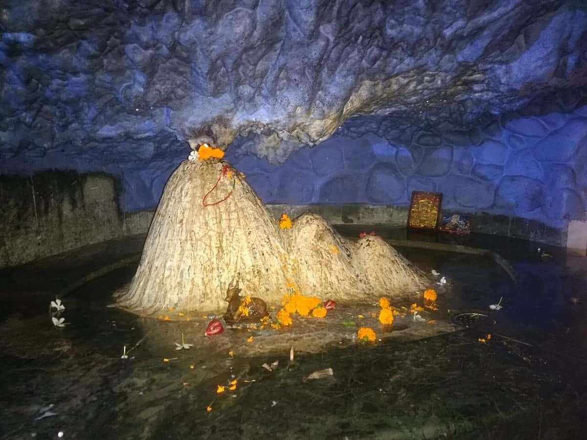 Shivling inside the Tapkeshwar Mahadev cave temple, with water dripping from the cave roof