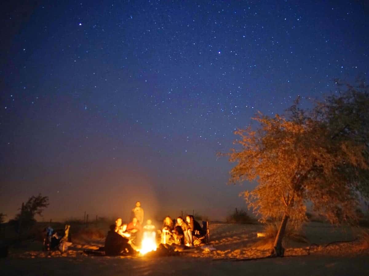 Campfire glowing under a starry night sky