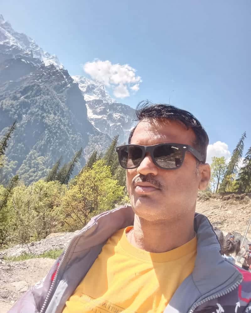 Deepak Swami, founder of Deepak Tour & Travel, with snow-capped mountains behind him