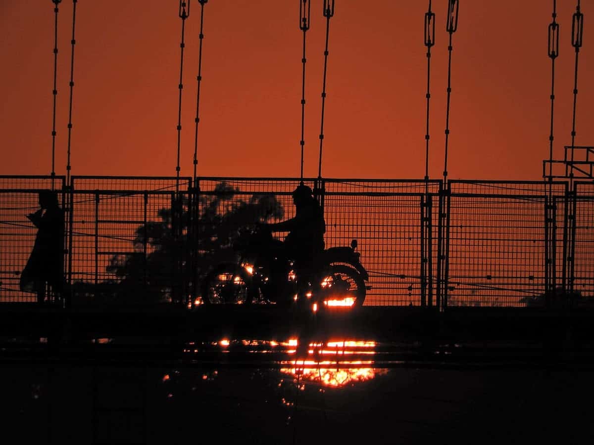 Riders silhouetted against the sunset on Ram Jhula, Rishikesh