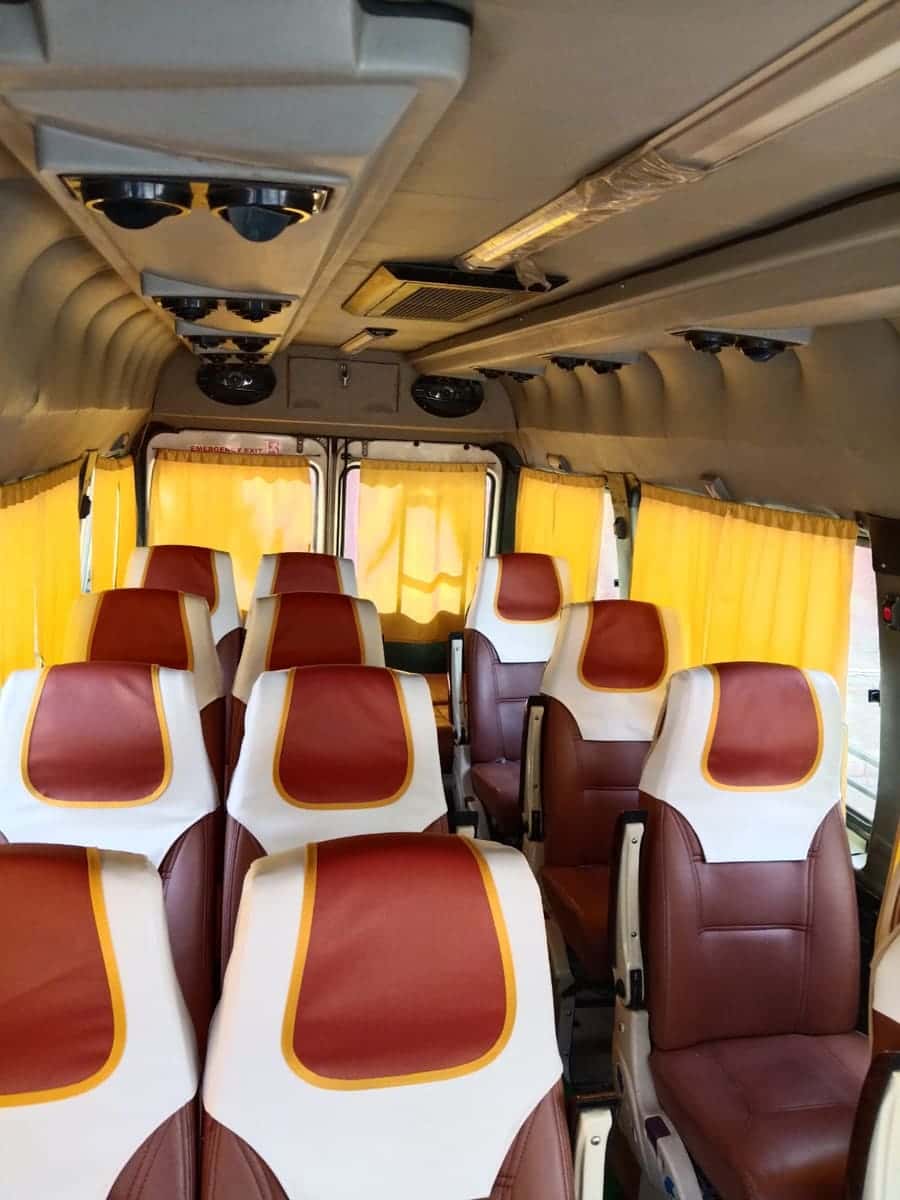 Inside the van: rows of rust-red and white seats with yellow trim and yellow curtains
